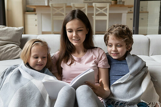 Mutter ließt mit Sohn und Tochter